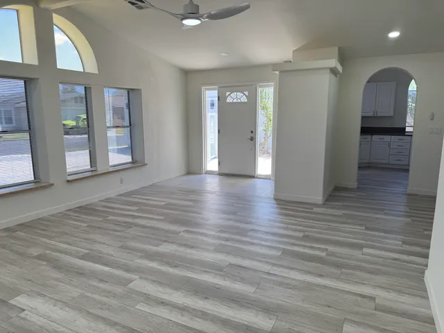 an empty room with wooden floor and windows