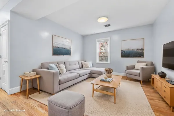 a living room with furniture a flat screen tv and a window