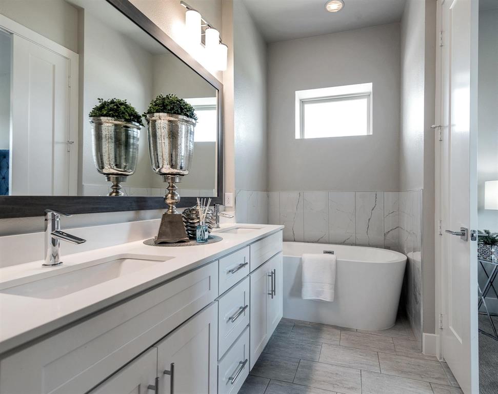 770 North Plano Road, Unit 303 Richardson, TX 75081 - Photo 14 of 26 Well-appointed bathroom featuring a double vanity with ample storage, a large mirror, and a freestanding bathtub against a tiled wall