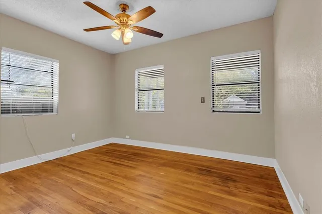 a view of an empty room with window and a chandelier fan