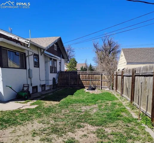a view of a house with a small yard and wooden fence