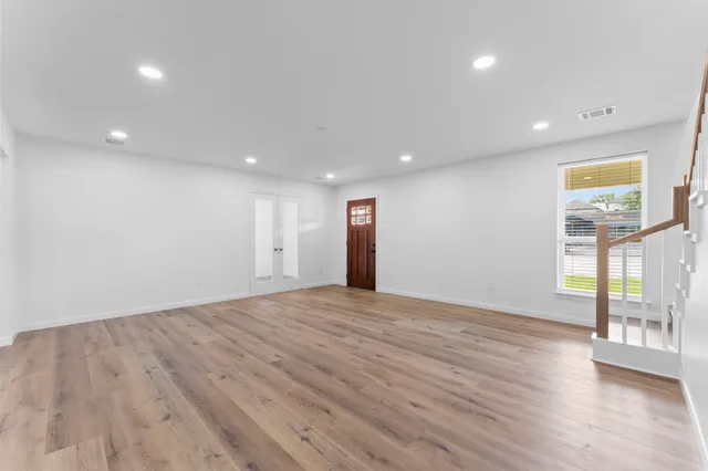 a view of an empty room with wooden floor and a window