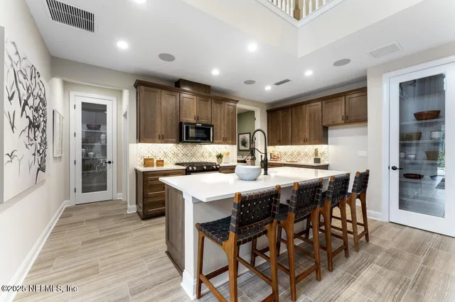 a kitchen with stainless steel appliances kitchen island granite countertop a table chairs sink refrigerator and cabinets