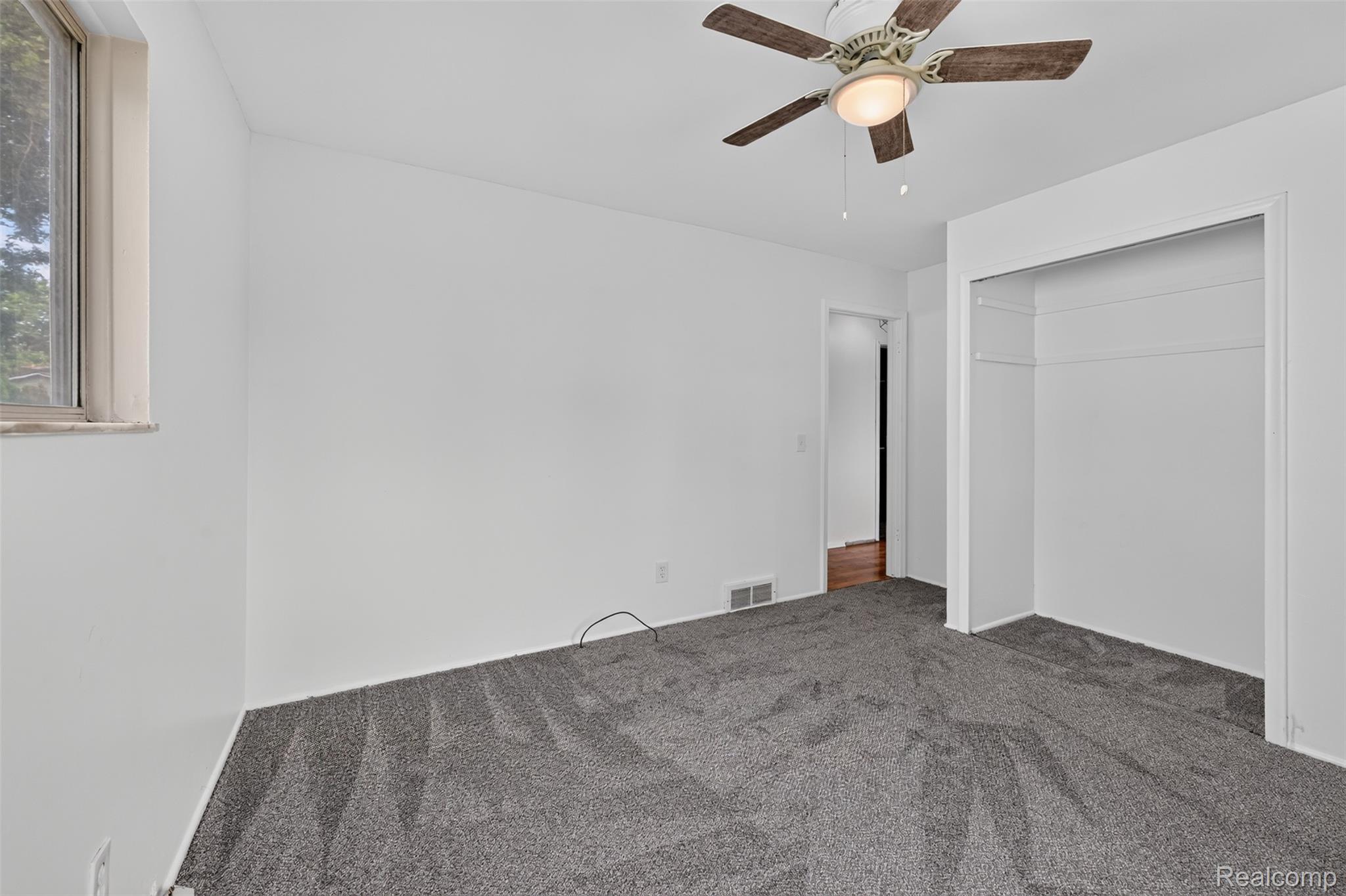 5457 Reid Road Swartz Creek, MI 48473 - Photo 31 of 51 Room featuring neutral gray carpeting, a window with a stone sill, and a ceiling fan with integrated lighting
