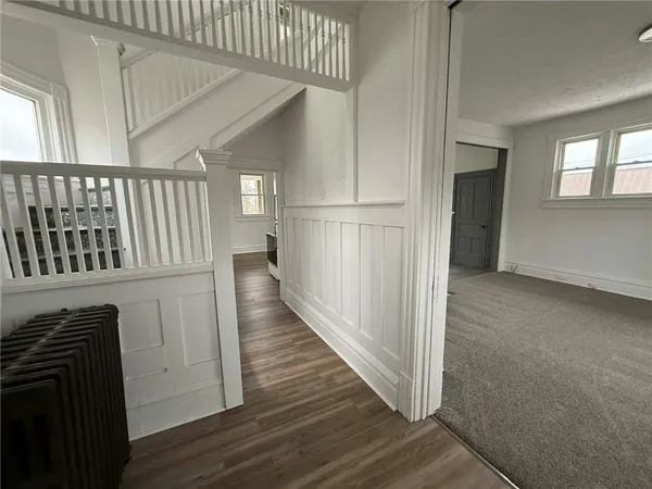 a view of a hallway with wooden floor and staircase
