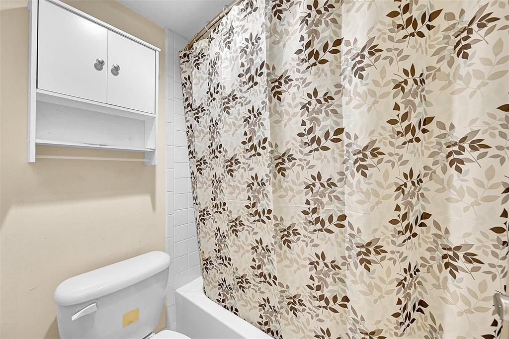 1901 Bermuda Circle, Unit F2 Coconut Creek, FL 33066 - Photo 19 of 26 a bathroom with a toilet and a shower curtain