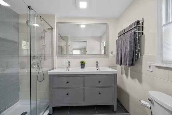 a bathroom with a sink a toilet a mirror and shower