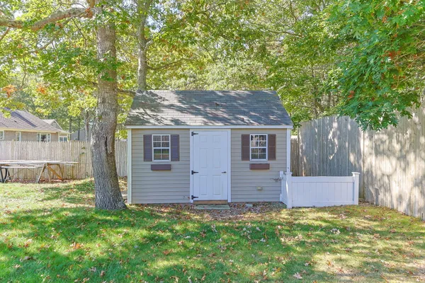a backyard of a house with large trees and wooden fence