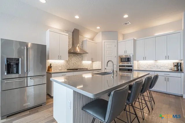a kitchen with kitchen island white cabinets and stainless steel appliances