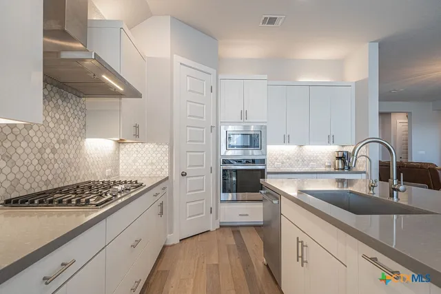 a kitchen with white cabinets and appliances