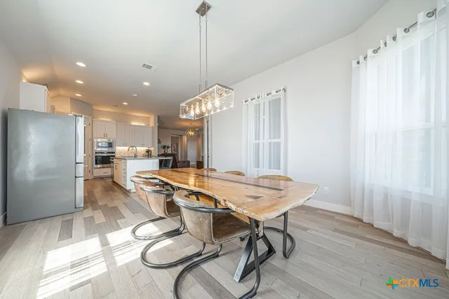 a dining room with stainless steel appliances kitchen island granite countertop a table chairs and a refrigerator