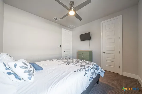 a bedroom with a bed and a flat tv screen on the dresser