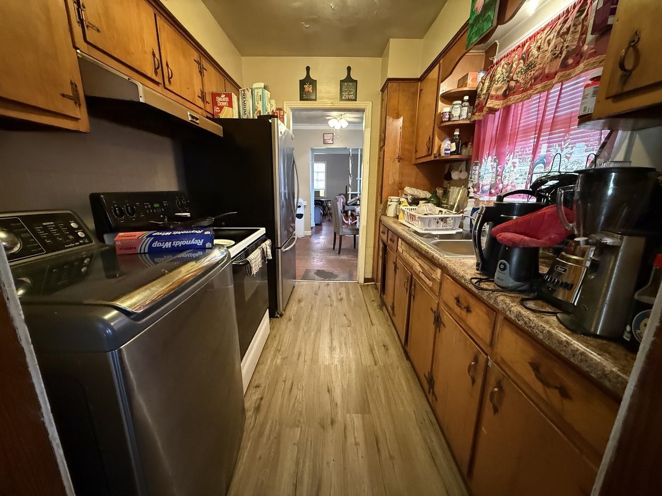 1309 Semmes Street Memphis, TN 38111 - Photo 6 of 24 Kitchen with brown cabinets, stainless steel range oven, under cabinet range hood, light wood finished floors, and separate washer and dryer