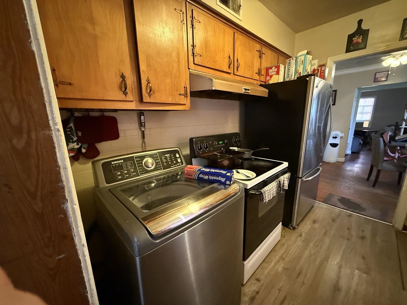 1309 Semmes Street Memphis, TN 38111 - Photo 8 of 24 Kitchen with washer / dryer, brown cabinetry, electric stove, light wood-style floors, and under cabinet range hood