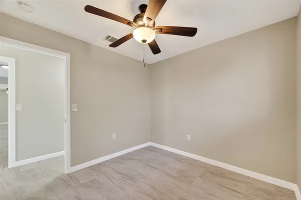 an empty room with a ceiling fan and wooden floor