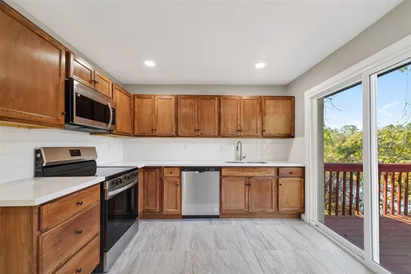 a kitchen with granite countertop cabinets stainless steel appliances a sink and a window