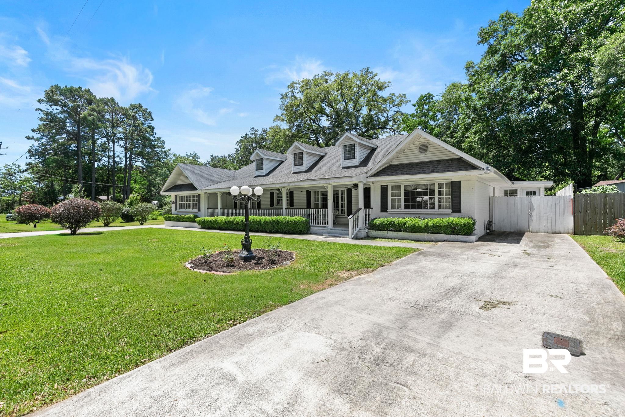 927 Cleveland Road Saraland, AL 36571 - Photo 1 of 80 Traditional-style residence featuring a prominent front porch with white columns, a dark shingle roof, and multiple dormer windows