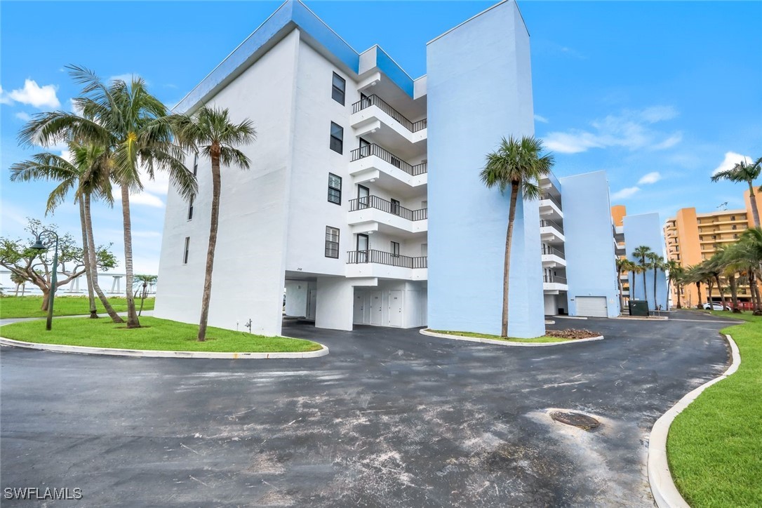 15010 Punta Rassa Road, Unit 108 Fort Myers, FL 33908 - Photo 2 of 30 a view of a white house with a yard and palm trees