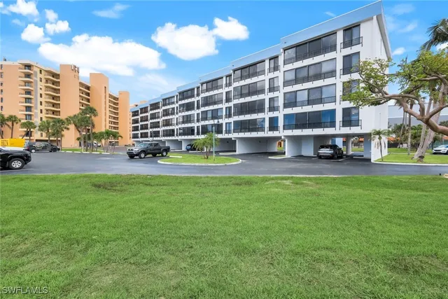 a view of an apartment with a big yard and large trees