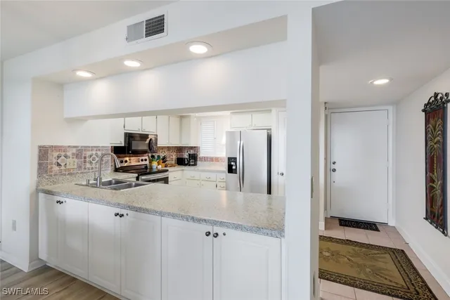 a kitchen with stainless steel appliances granite countertop a sink and a refrigerator