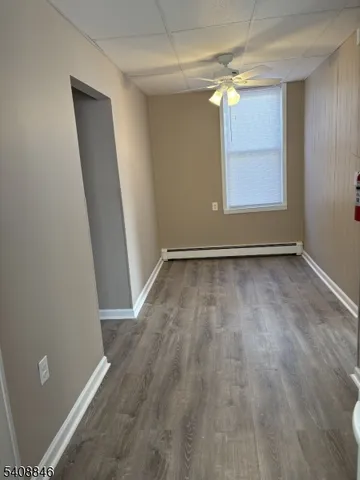 an empty room with wooden floor fan and windows