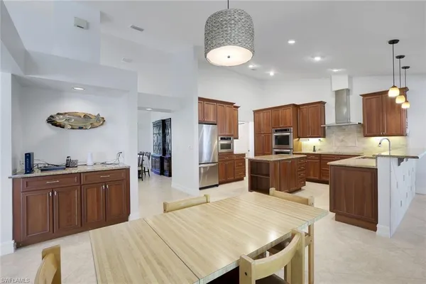 a kitchen with stainless steel appliances kitchen island granite countertop a sink dishwasher stove top oven and refrigerator