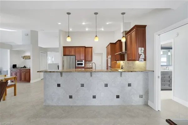 a large kitchen with stainless steel appliances kitchen island granite countertop a refrigerator and a stove top oven