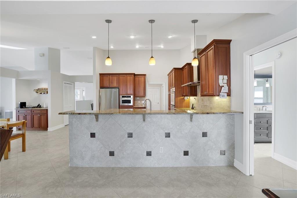 1819 Princess Court Naples, FL 34110 - Photo 4 of 25 a large kitchen with kitchen island a large counter space and stainless steel appliances