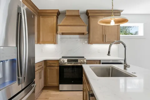 a kitchen with stainless steel appliances granite countertop a sink a stove and a refrigerator