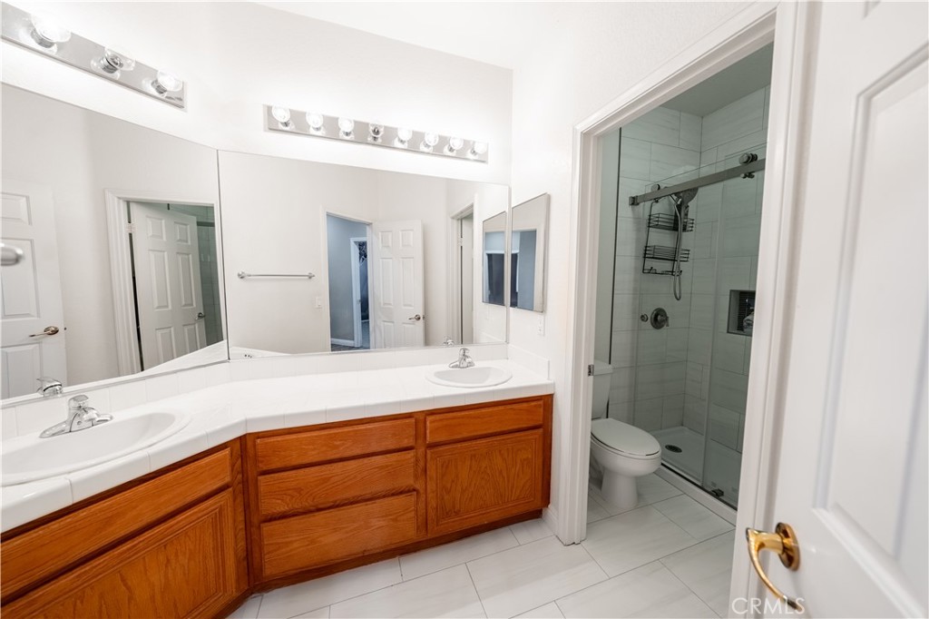 31465 Inverness Court Temecula, CA 92591 - Photo 29 of 71 a bathroom with a granite countertop sink toilet mirror and bathtub