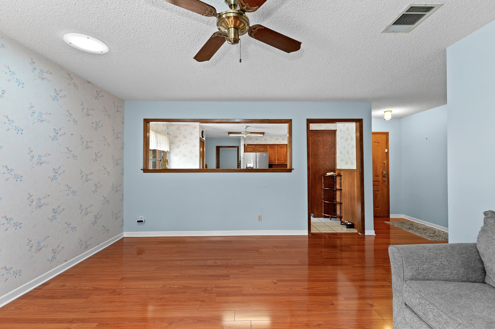 5600 Libyan Circle Austin, TX 78745 - Photo 9 of 37 Unfurnished living room featuring a ceiling fan, a textured ceiling, wood finished floors, and wallpapered walls