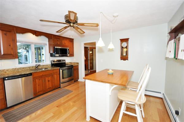5 Bromfield Road Acton, MA 01720 - Photo 2 of 9 a kitchen with stainless steel appliances granite countertop a stove top oven a sink a dining table and chairs with wooden floor