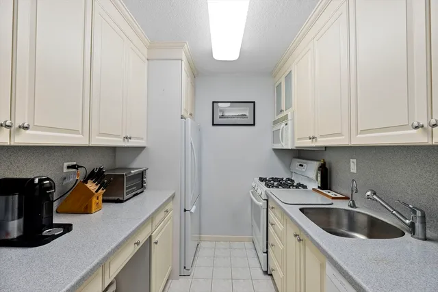 a kitchen with white cabinets and sink