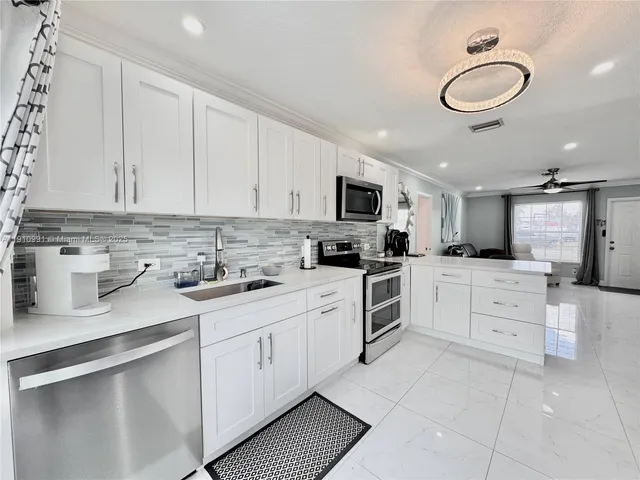 a kitchen with white cabinets stainless steel appliances and sink