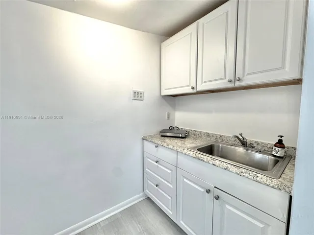 a kitchen with white cabinets and sink