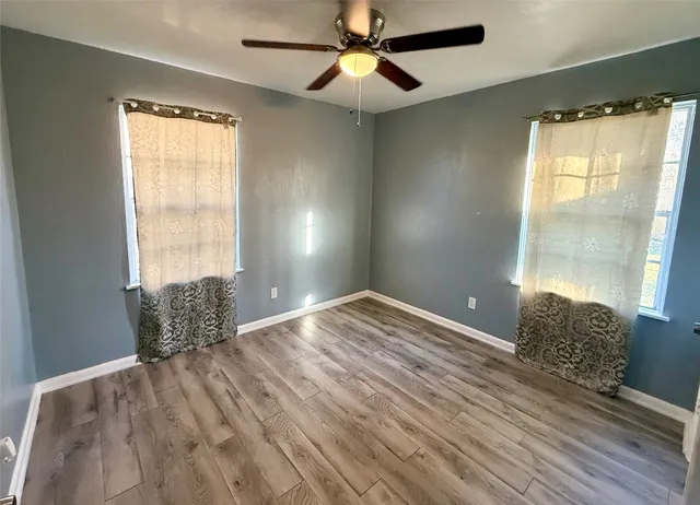 a view of empty room with wooden floor and fan
