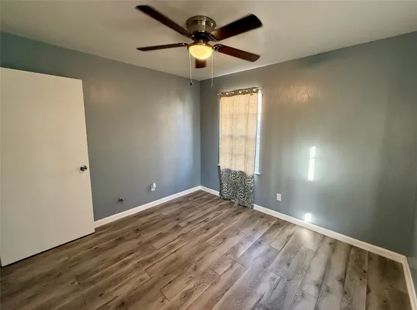 a view of an empty room and window and chandelier fan
