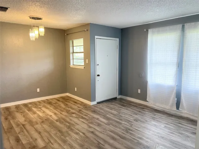 a view of an empty room with window and wooden floor