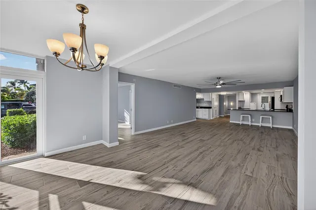a view of empty room with wooden floor and fan