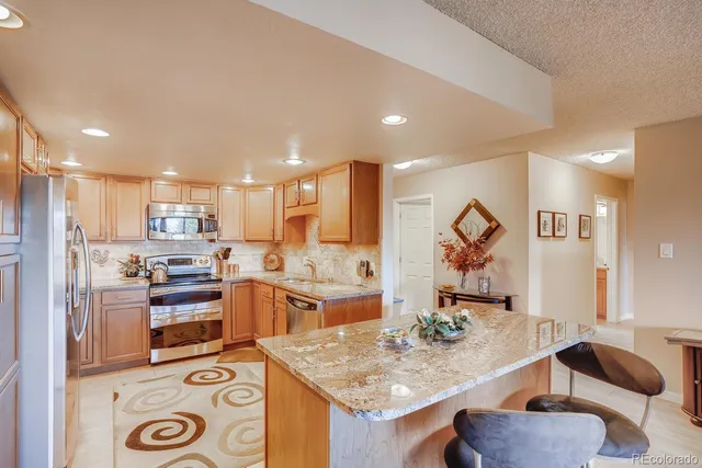 a kitchen with stainless steel appliances granite countertop a sink stove and refrigerator