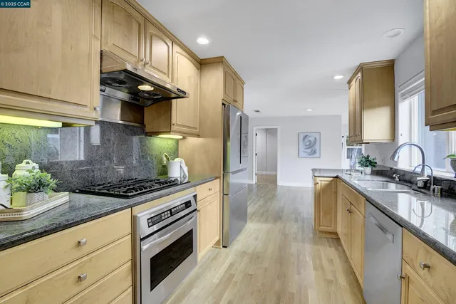 a kitchen with stainless steel appliances granite countertop a sink a stove and a wooden floors