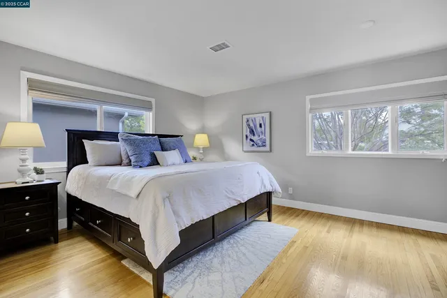 a spacious bedroom with a bed and a lamp on dresser