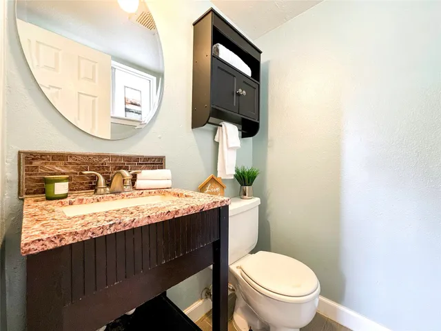 a bathroom with a granite countertop toilet sink and mirror