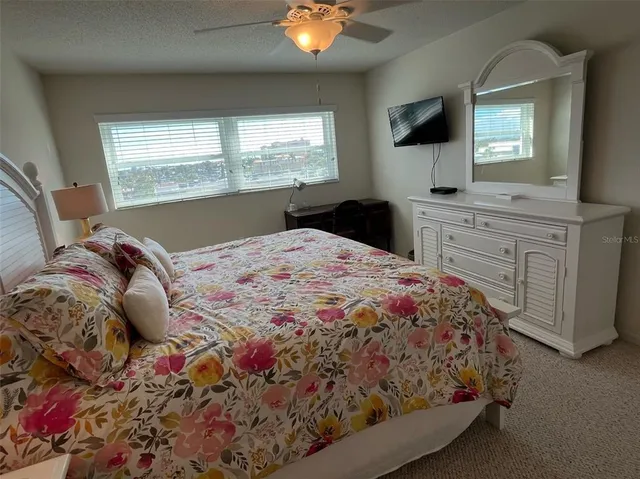a bedroom with a large bed and a flat tv screen on dresser