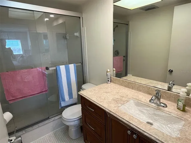 a bathroom with a granite countertop bathtub sink vanity mirror and toilet