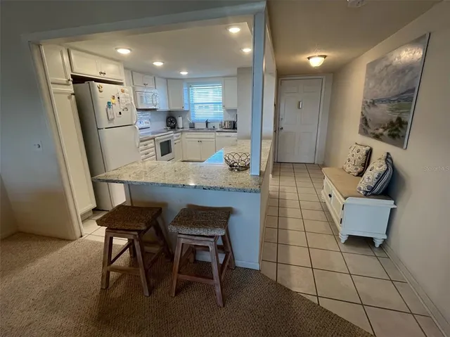 a kitchen with stainless steel appliances granite countertop a refrigerator and a stove top oven with white cabinets