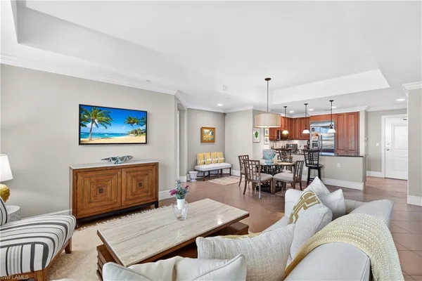 a living room with furniture a rug kitchen view and a chandelier