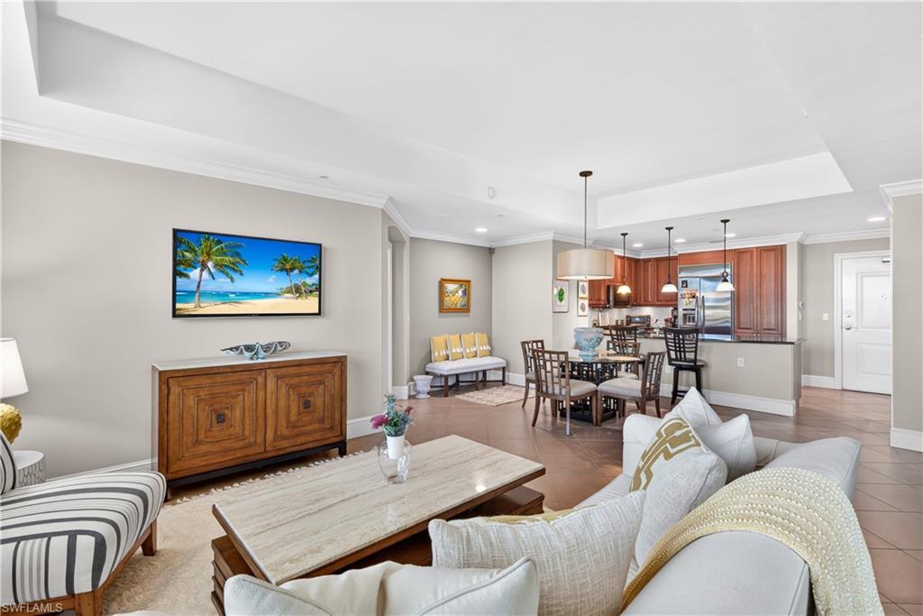 9115 Strada Place, Unit 5504 Naples, FL 34108 - Photo 1 of 22 a living room with furniture a rug kitchen view and a chandelier