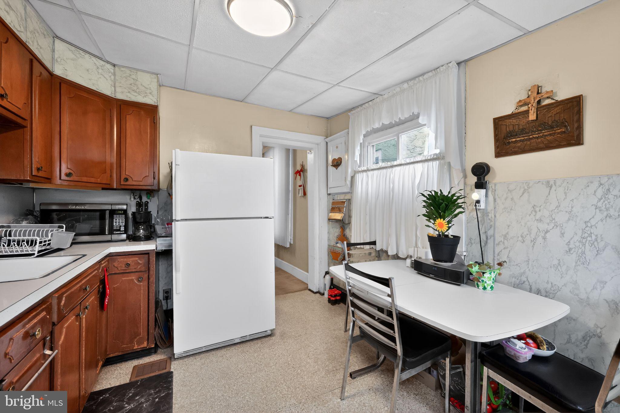 3067 Cedar Street Philadelphia, PA 19134 - Photo 15 of 30 a kitchen with stainless steel appliances granite countertop a refrigerator a sink a stove a dining table and chairs with wooden floor