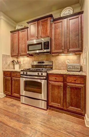 a kitchen with stainless steel appliances granite countertop a stove a sink and a microwave